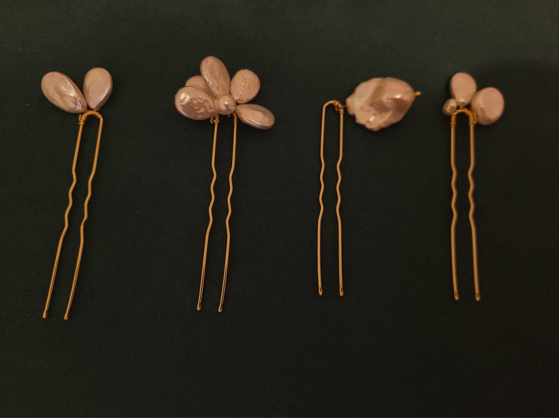 Set of five floral hairpins with decorative elements on a dark background