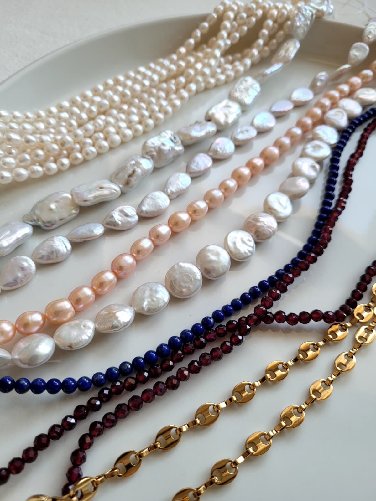 Collection of various pearl necklaces on a white surface