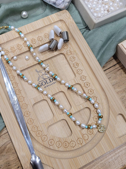 Pearl necklace with gold accents on a wooden jewelry display tray.
