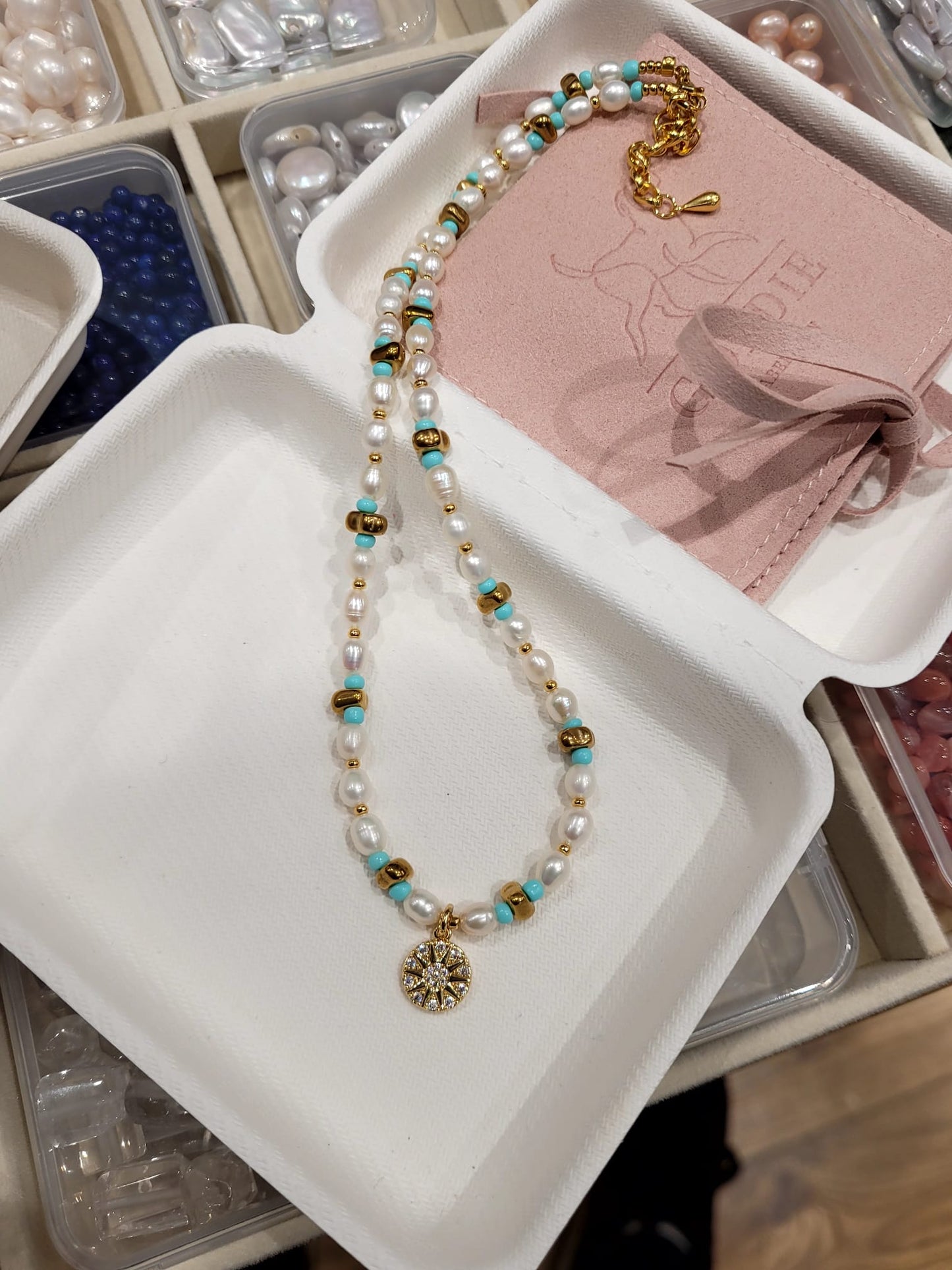 Necklace with pearls and turquoise beads on a white tray with jewelry-making materials.