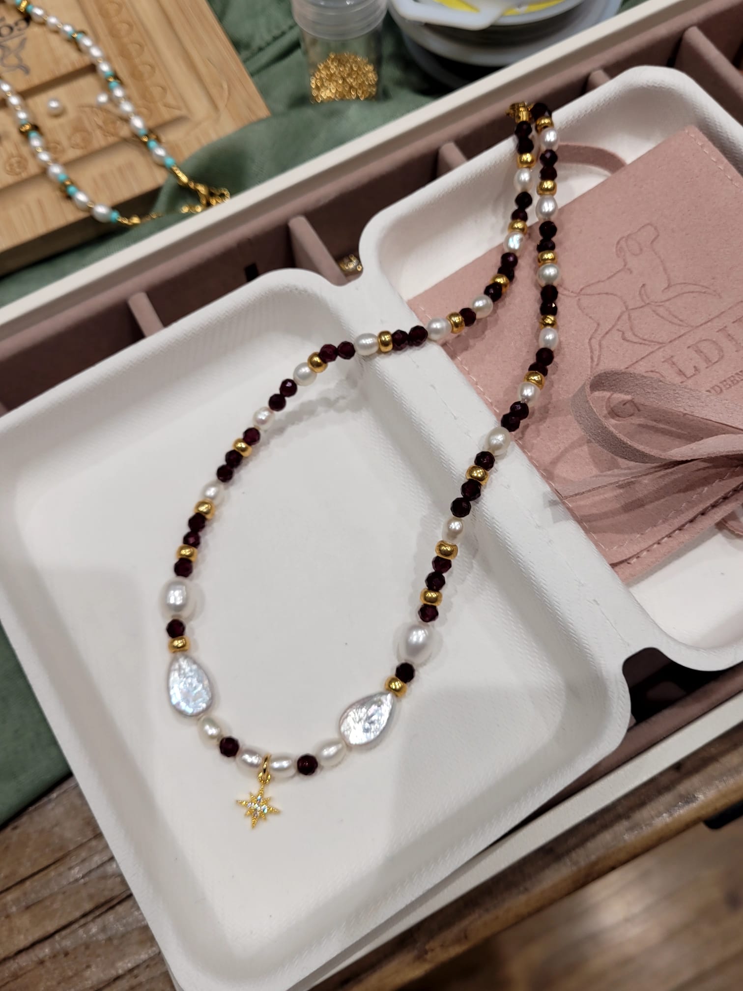 Necklace with beads on a white tray with a wooden surface in the background